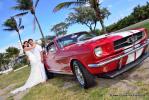 Ford Mustang in Rot mit Hochzeitspaar unter Palmen